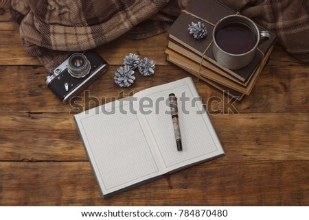 Diary with pen, books, aluminum vintage cup with hot tea, antique photo camera and Christmas bumps on a wooden background.