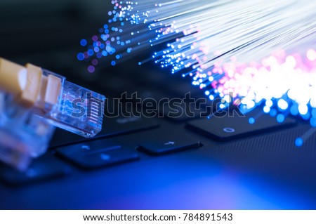 Yellow internet connection cable  on laptop ,defocused optical fibre background. Royalty-Free Stock Photo #784891543