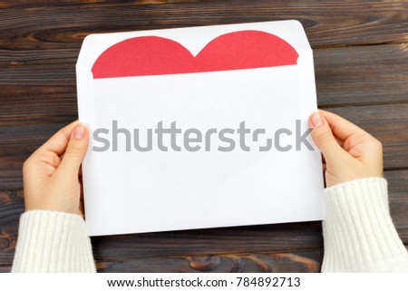 Empty postcard in hand with heart. On the wooden table. top view and copy space.