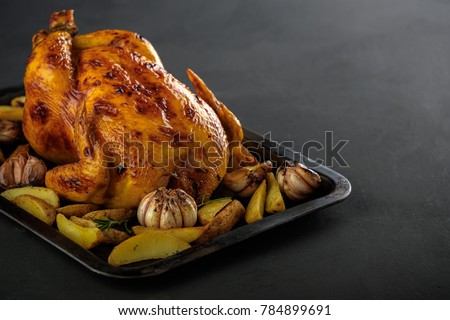 Roasted chicken with potatoes on a baking sheet. Copyspace. Royalty-Free Stock Photo #784899691