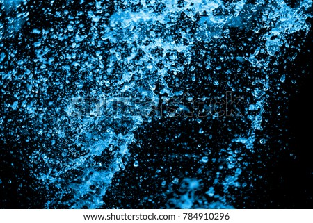 blue water splash on the black background.  Close up Jet of water from hose use for abstract background.