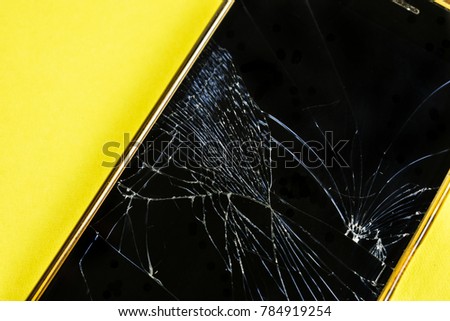 Phone on the yellow table with broken glass