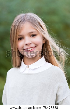 Child in grey sweater on idyllic autumn day. Girl with blond long hair smile on natural landscape. Happy childhood concept. Beauty, youth, growth. Kid fashion and style.