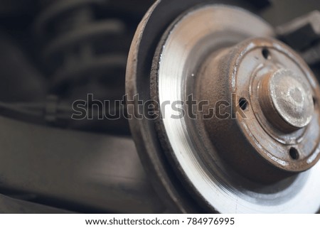 car wheel brake disc and shoes of lifted automobile at repair service station.