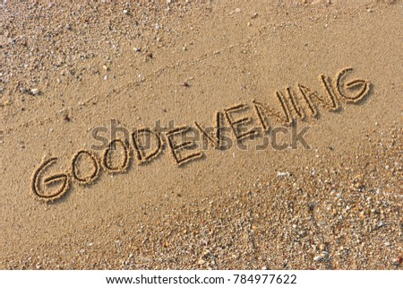 Handwriting  words "GOOD EVENING" on sand of beach.