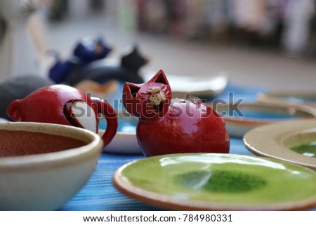 The shelf with Greek hand-made souvenirs - colorful ceramic cups and plates with pictures of owl, animals and flowers.