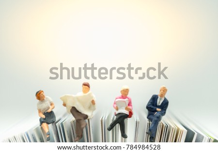 Miniature people: Business team sitting on book, reading news paper with copy space using as background business, education concept. Royalty-Free Stock Photo #784984528