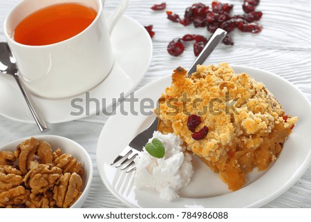 gluten free healthy  breakfast - a portion of apple crumble or apple crisp on plate with coconut ice cream and cup of tea on table, close-up