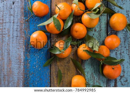 Tangerines (oranges, mandarins, clementines, citrus fruits) with leaves in basket over rustic wooden background, copy space
