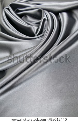 Smooth elegant dark grey or silver silk or satin luxury cloth fabric texture, abstract background design.