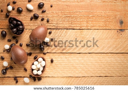 Easter concept painted and chocolate eggs, sweets, drops, candys, bunny for holiday with place for text pattern on wooden background