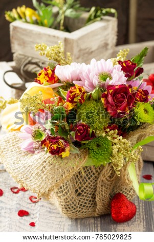 Background wedding or Valentine's Day. Basket bouquet of roses and chrysanthemums on a vintage wooden background.