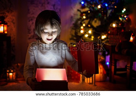 Two children, boy brothers, opening Christmas presents, magical light from inside