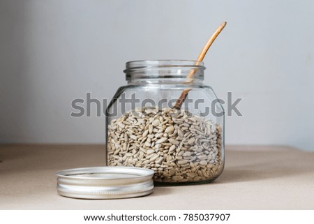 Sunflower seeds in glass jar with wooden spoon and space for text
