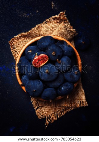 Ripe blue fresh figs in a wooden bowl, dark background, top view