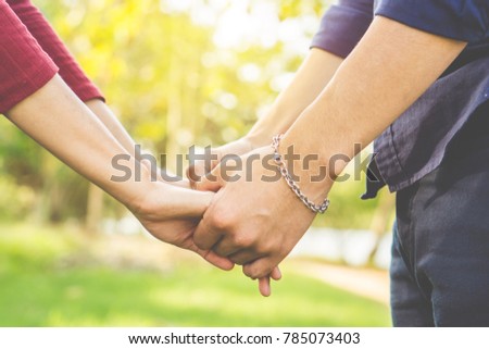 young couple in love holding hand together  walking in a beautiful park with romantic nature background 
