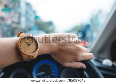 fashion background young business women wearing wooden watch and driving car. image for equipment, accessory, retro, classic, transportation, body, vehicle concept