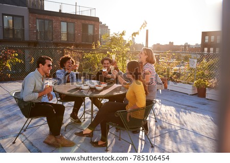 Five friends sitting at a table on a rooftop making a toast Royalty-Free Stock Photo #785106454