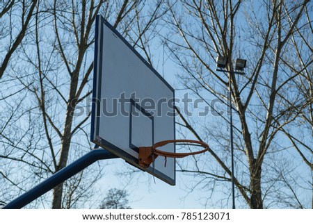 Old outdoor basketball court with tree ranches and blue sky in the background. Virtual games, increased social network activity concept