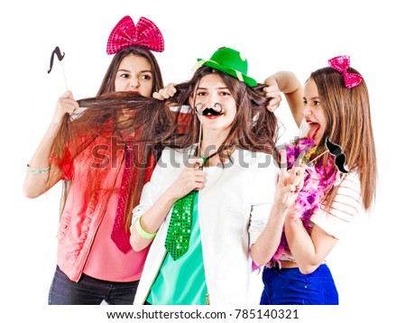 Girls enjoy doing silly on white background. They make jokes and grimaces, enjoying the holiday. They are friends, and they imitate the mustache with their hair