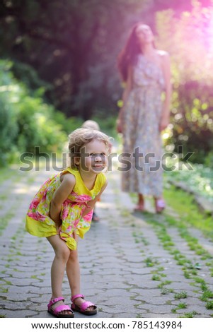 Happy daughter girl with blond curly hair, in summer dress walk with mother on idyllic day on natural landscape. Outdoor fun, leisure, lifestyle. Child, childhood, concept. Family, love, mothers day