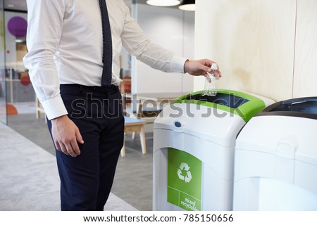 Man in an office throwing plastic bottle into recycling bin Royalty-Free Stock Photo #785150656