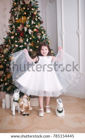 The beautiful girl near a Christmas tree. New year. The girl in a beautiful white dress