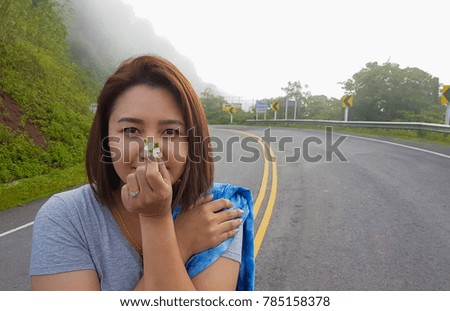Fashion portrait pretty cute young Asian woman hand holding beautiful small flowers  on mountain peak,copy space. inspiration,vacation,travel in Asia concept. raining day and inspiration concept. 