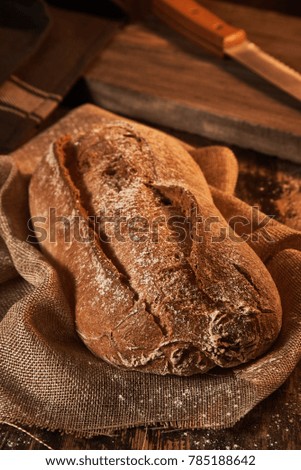 Delicious bread rye loaf with crust served on canvas towel on wooden surface.