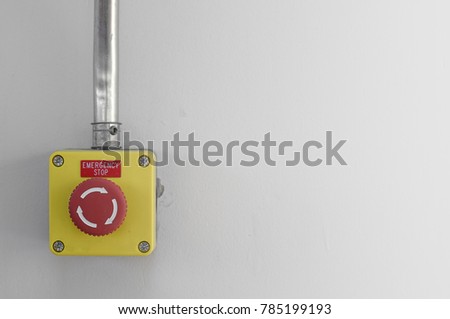 Emergrncy stop button on white wall ,use for emergency stop the machine or process in manufacturing.