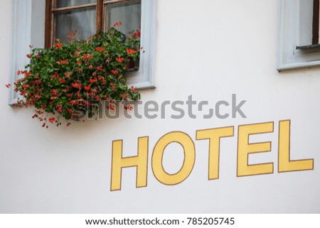 A Hotel sign with a beautiful hanging basket of flowers.