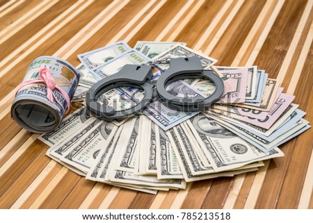 handcuffs with dollar bills on desk. close up Royalty-Free Stock Photo #785213518