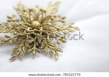 Golden snowflake in macro closeup on a white background. Soft image, christmas and happy new year. High resolution photography.