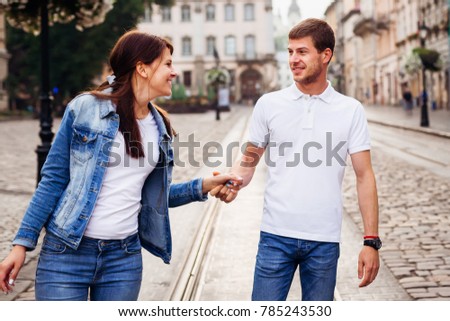 A smiling girl takes a hand of her lover and they go for a walk around the city
