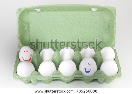 Green cardboard package for eggs with eggs with painted colored smileys