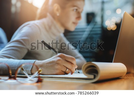Close up of young woman working at her office desk with documents and laptop
