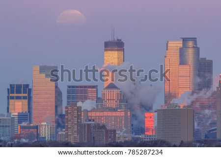 A Telephoto Shot of the Minneapolis Skyline Reflecting the Sunrise as the Moon Sets into a Hazy Winter Morning