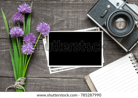 vintage retro camera with blank photo frame, purple wildflowers and lined notebook on rustic wooden background. mock up. top view