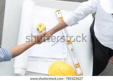 Top view architect and the engineering contractor shaking hands on building project and tools background. Concept of success and cooperation.