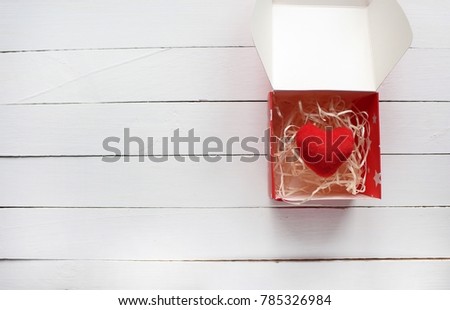 red heart in an open box on a white wooden background 
