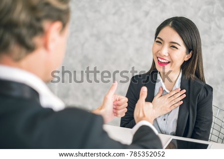 Boss/Business man employer admires young Asian business woman/staff/employee by thumb up and hands clap with smiling face for her success and good/best in work and recognition/appreciate. Royalty-Free Stock Photo #785352052