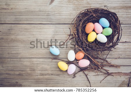 Colorful Easter eggs in nest on rustic wooden planks background. Holiday in spring season. vintage color tone style. top view composition.