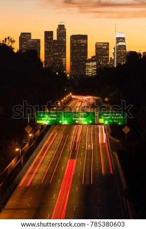 Light streaks from brake lamps flow across the foreground ad sunset falls on Los Angeles