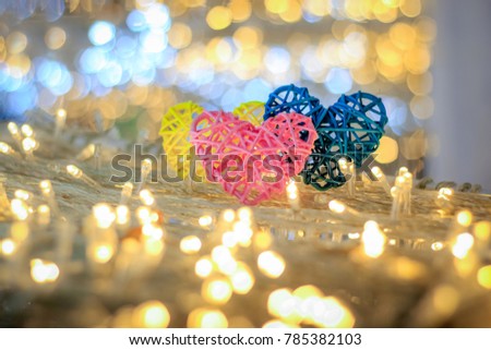 Abstract blurred bokeh and heart background for valentine love concept.Soft focus Three heart sharp hand made bamboo theee color pink,yellow and blue in circle bokeh led background with copy space.