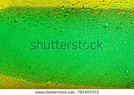 Water droplets on glass with a bright green and yellow background