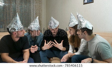 Group of people with foil on their heads discussing conspiracy theories. Friends with foil on their heads. You know, so they can't read your mind Royalty-Free Stock Photo #785406115