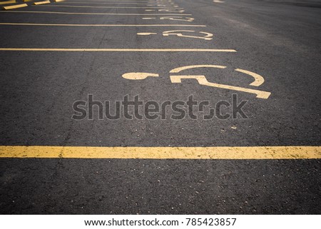 YELLOW HANDICAPPED SIGNS ON BLACK ASPHALT PARKING AREA