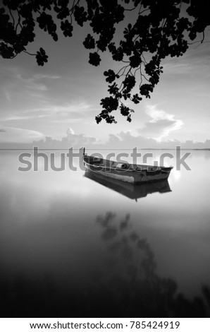 Fine art image in black & white of traditional fishing boat with nature framing at Tumpat Kelantan, Malaysia. Soft Focus due to long exposure. 