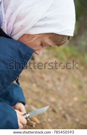 Little girl carefully carving a wooden toy outdoors