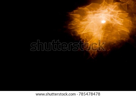 Orange bokeh that looks like a falling moon, on a black background